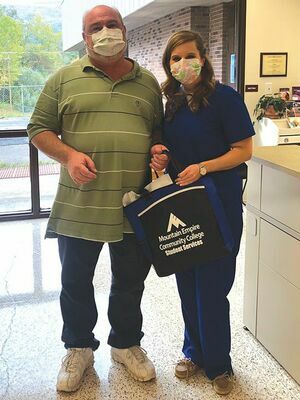 Fred Tolliver (left) receives a patient bag from Emily Bowen.